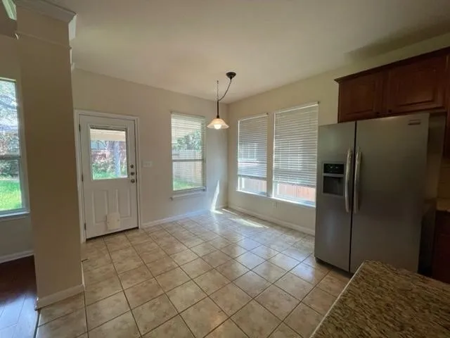 a view of a refrigerator in kitchen and an empty room in wooden floor