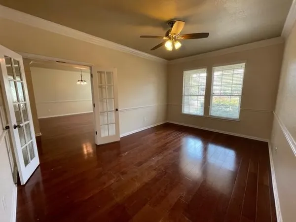 an empty room with wooden floor and windows