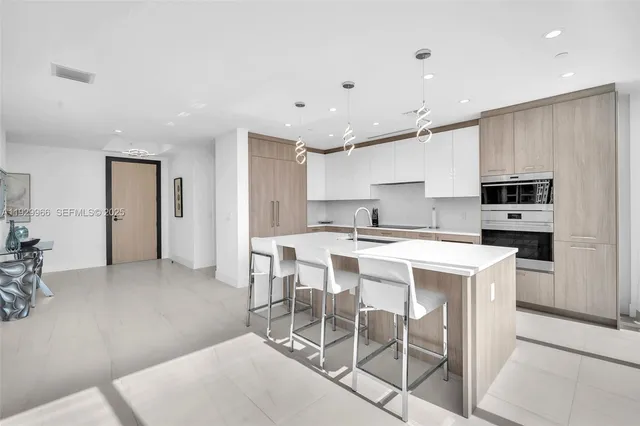 a kitchen with stainless steel appliances kitchen island granite countertop a stove a refrigerator a white table and chairs