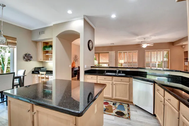 a kitchen with stainless steel appliances granite countertop a refrigerator a stove and white cabinets with wooden floor