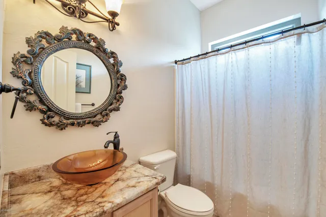a bathroom with a granite countertop sink toilet and a mirror