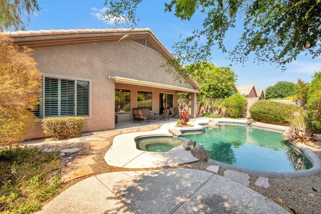 a view of swimming pool with lawn chairs and plants