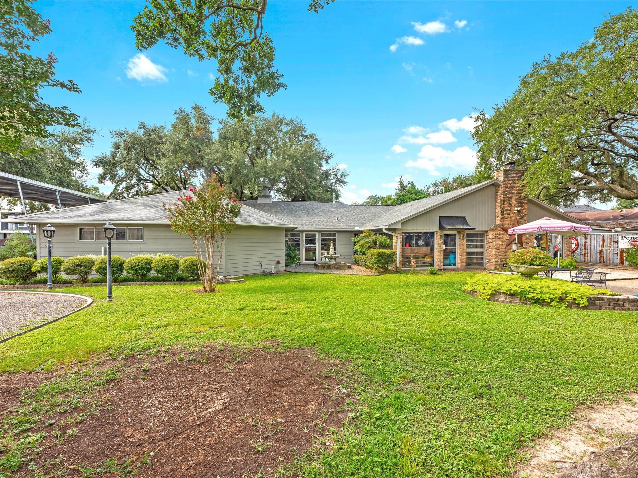 810 Martin Street Houston, TX 77018 - Photo 3 of 31 The backyard offers a spacious, open lawn surrounded by mature trees and manicured landscaping, creating a peaceful retreat. A charming brick chimney adds character to the home’s exterior, while the covered patio and open seating area provide the perfect spots for outdoor dining and entertaining. The large windows bring in natural light and offer picturesque views of the yard, making this space ideal for both relaxation and gatherings