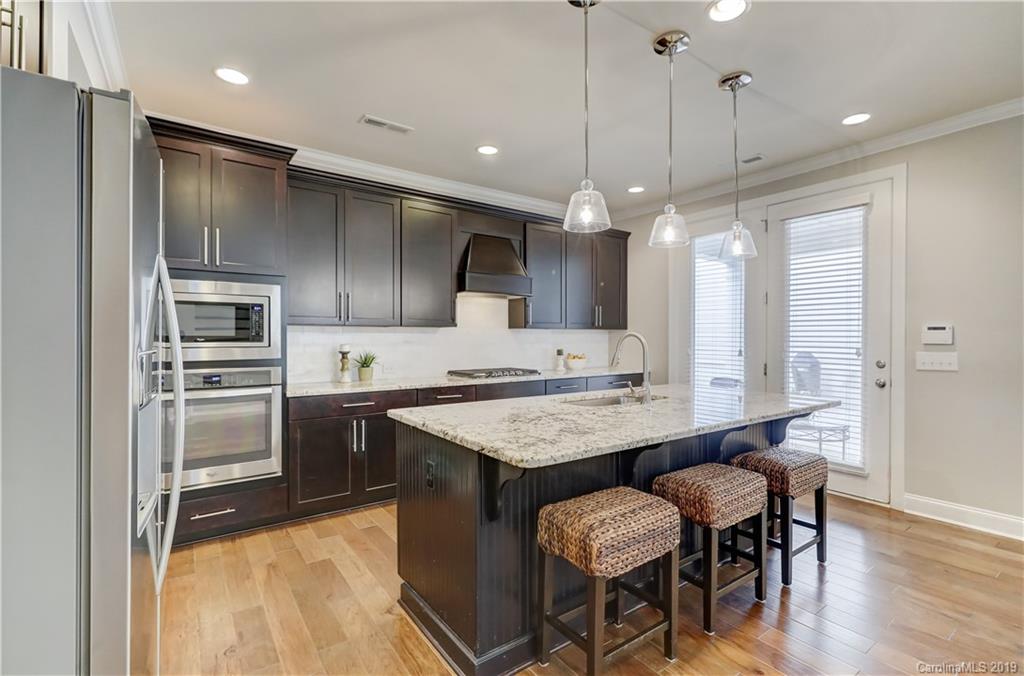 108 Helton Lane Fort Mill, SC 29708 - Photo 14 of 48 a kitchen with granite countertop a table chairs stainless steel appliances and wooden floor