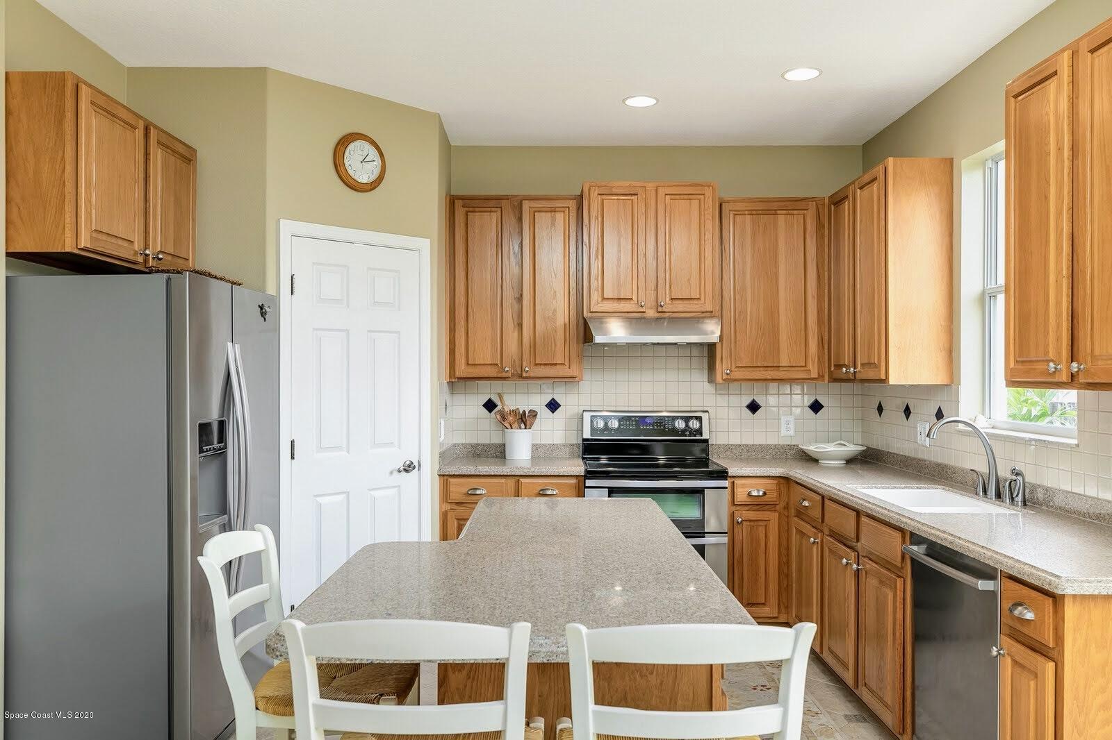 230 Richards Road Melbourne Beach, FL 32951 - Photo 7 of 42 a kitchen with stainless steel appliances granite countertop a stove a sink a refrigerator white cabinets and wooden floor