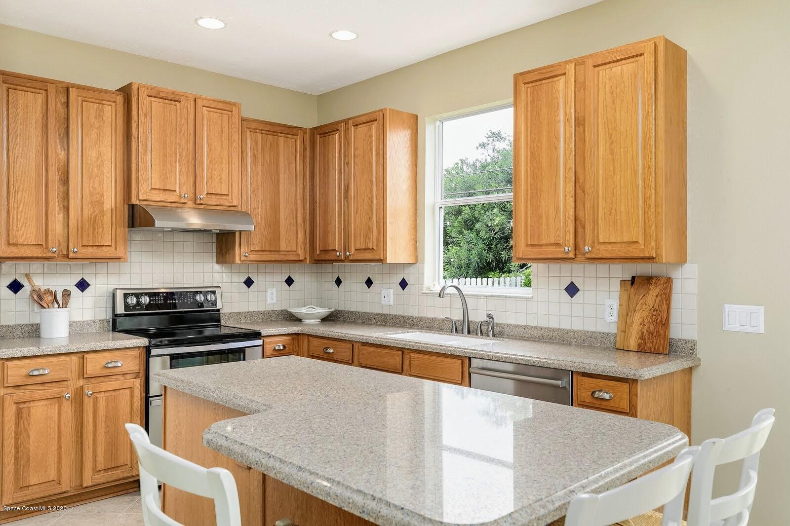 230 Richards Road Melbourne Beach, FL 32951 - Photo 8 of 42 a kitchen with stainless steel appliances granite countertop a sink a stove and white cabinets