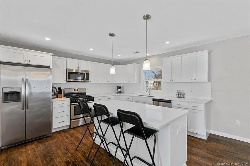 a kitchen with stainless steel appliances kitchen island a table chairs refrigerator and microwave