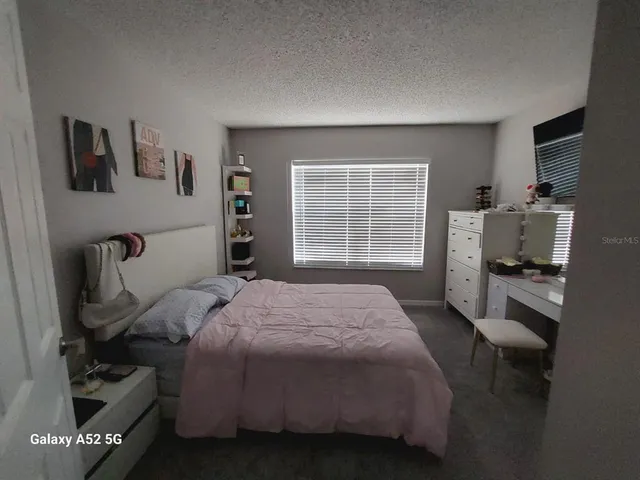 a bedroom with a bed a dresser and next to a window