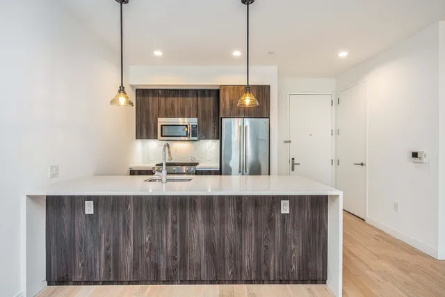 a kitchen with stainless steel appliances granite countertop a sink a refrigerator and a wooden floor