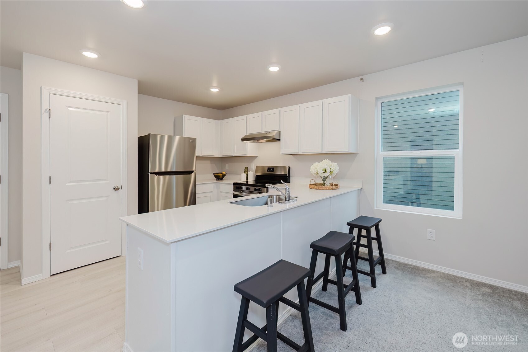 240 Northeast Olympic Ridge Belfair, WA 98528 - Photo 15 of 28 a kitchen with a refrigerator a microwave oven a sink and a dining table with wooden floor