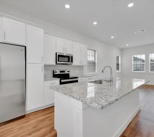 a kitchen with granite countertop white cabinets and stainless steel appliances