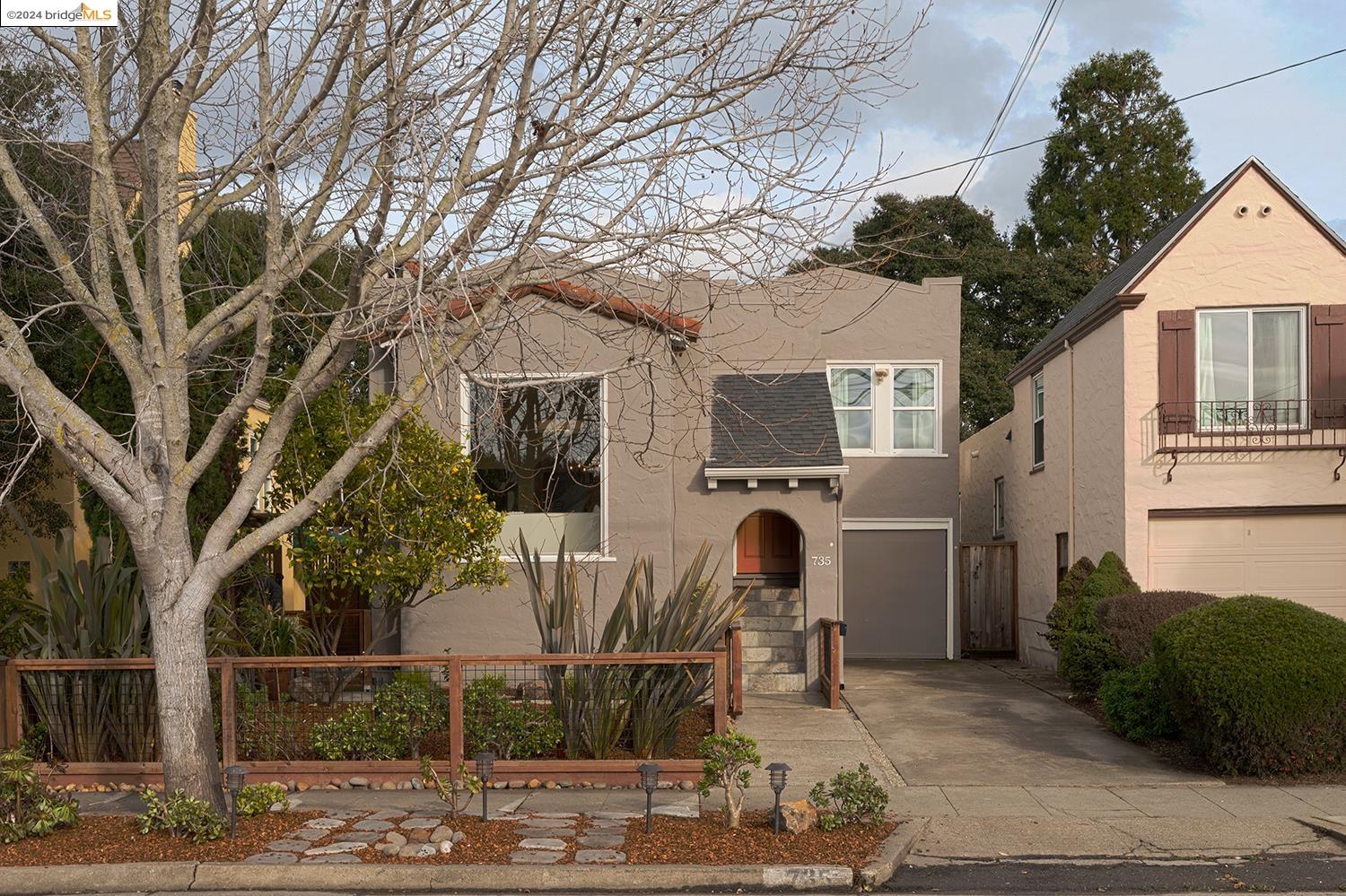 a view of a white house with a large tree and wooden fence