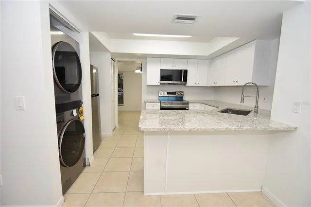 a kitchen with granite countertop a sink a stove and a microwave