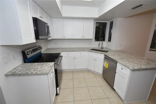 a kitchen with granite countertop a sink a stove and cabinets