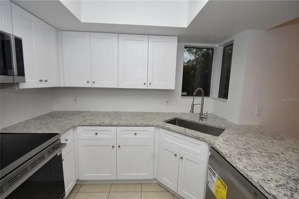 a kitchen with granite countertop white cabinets and a sink