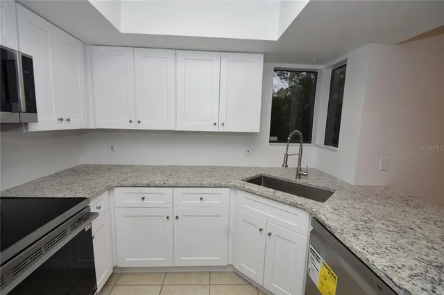 a kitchen with granite countertop white cabinets and a sink