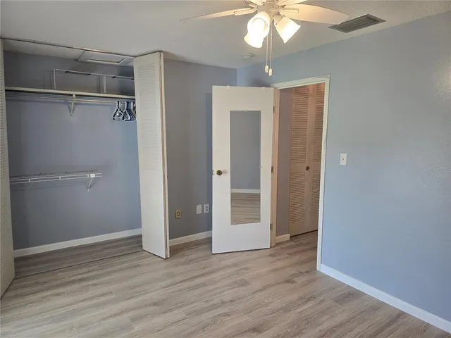 an empty room with wooden floor fan and windows