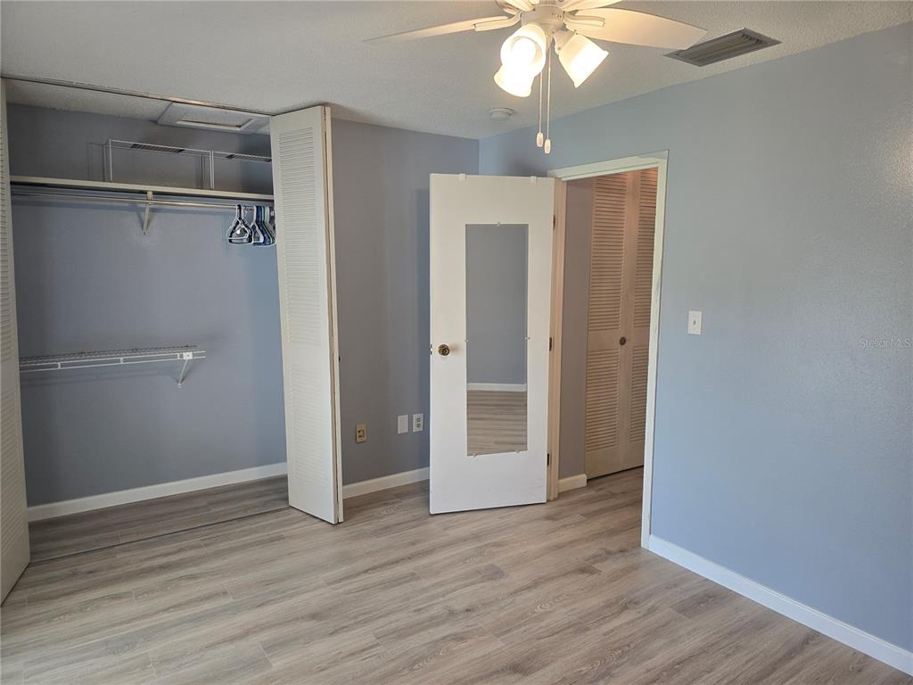 2700 Bayshore Boulevard, Unit 1302 Dunedin, FL 34698 - Photo 18 of 40 an empty room with wooden floor fan and windows