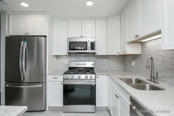 a kitchen with refrigerator a microwave a sink and cabinets