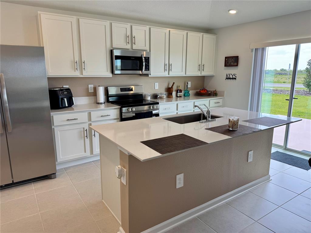 2405 Bluestone Road Haines City, FL 33844 - Photo 4 of 17 a kitchen with stainless steel appliances a stove a sink a microwave a refrigerator and cabinets