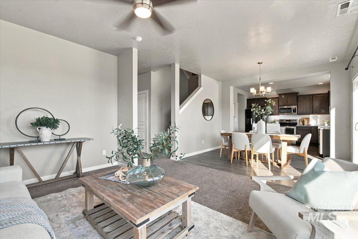 124 South Sunset Point Way Meridian, ID 83642 - Photo 8 of 24 Open-concept living area featuring a ceiling fan with integrated lighting, wood-finish flooring, and a staircase