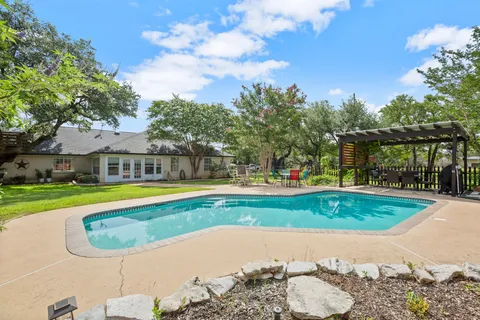 a view of a swimming pool with a yard and large trees