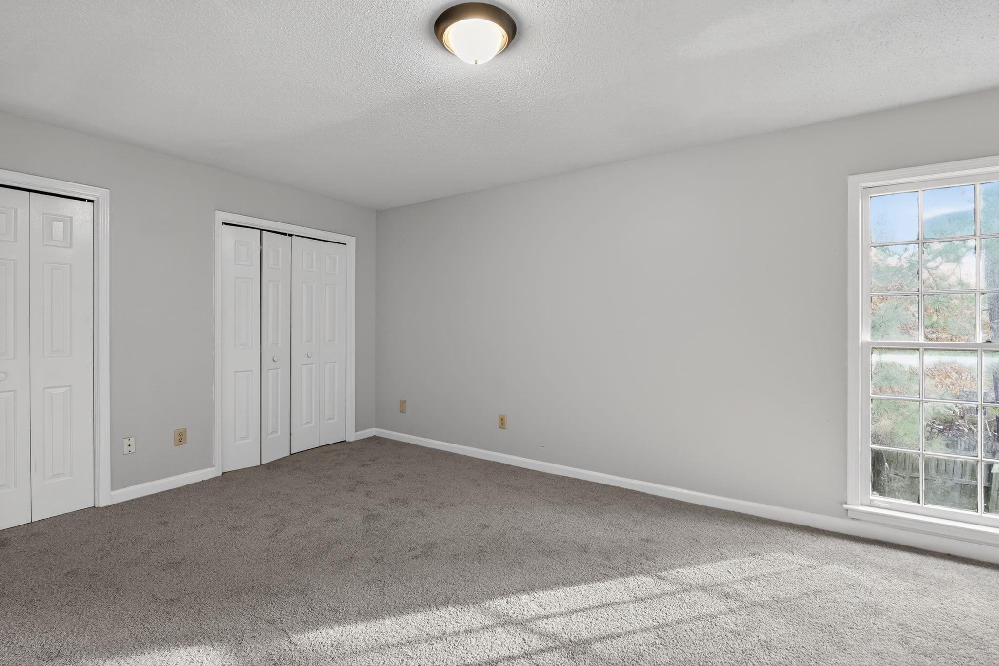 5581 Crepe Myrtle Drive Memphis, TN 38115 - Photo 23 of 33 Unfurnished bedroom with two closets, a textured ceiling, and carpet flooring
