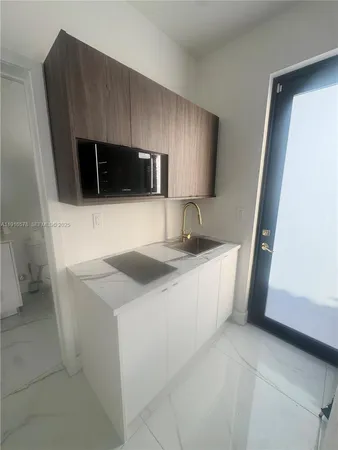 a kitchen with a sink a microwave a refrigerator and cabinets