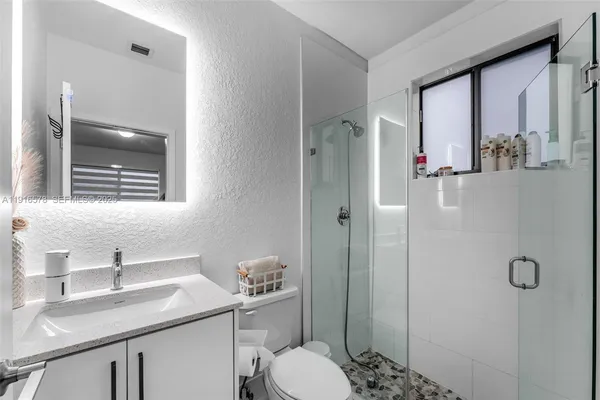 a bathroom with a granite countertop sink toilet and shower