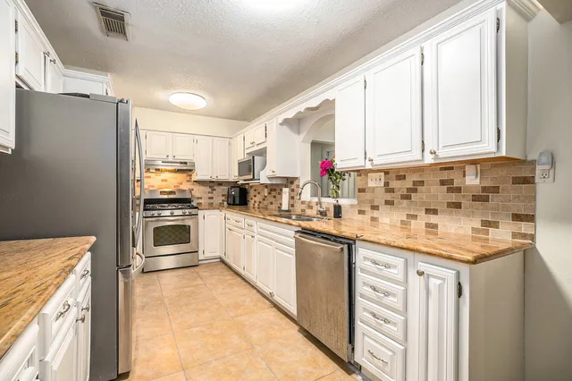 a kitchen with granite countertop a sink stainless steel appliances and cabinets