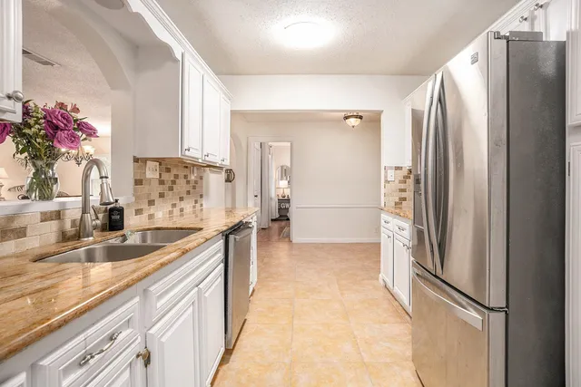 a kitchen with granite countertop a refrigerator and a sink