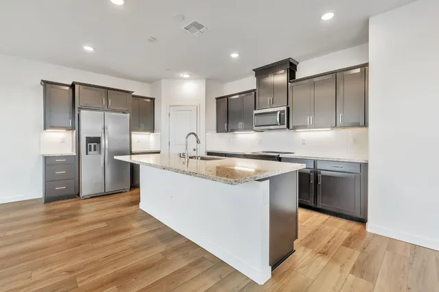 a large kitchen with stainless steel appliances kitchen island granite countertop a large counter top and wooden cabinets