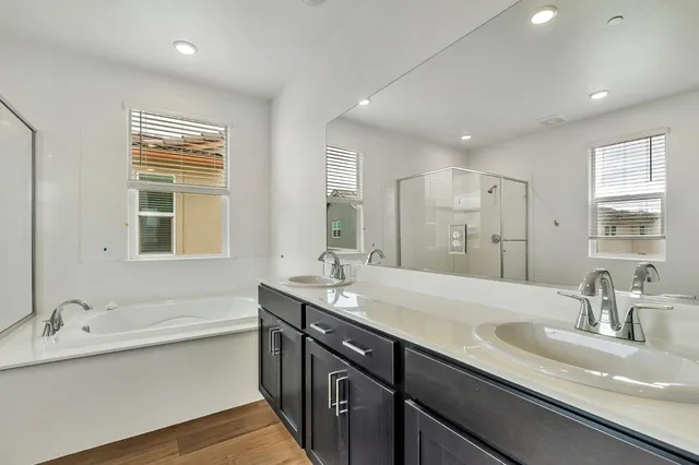 a bathroom with a sink double vanity granite tub shower and a mirror