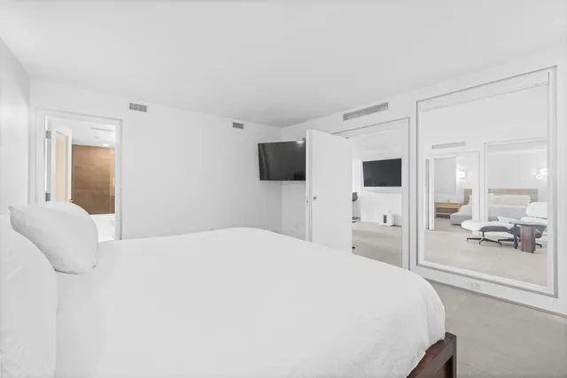 a spacious bedroom with a bed and a flat tv screen