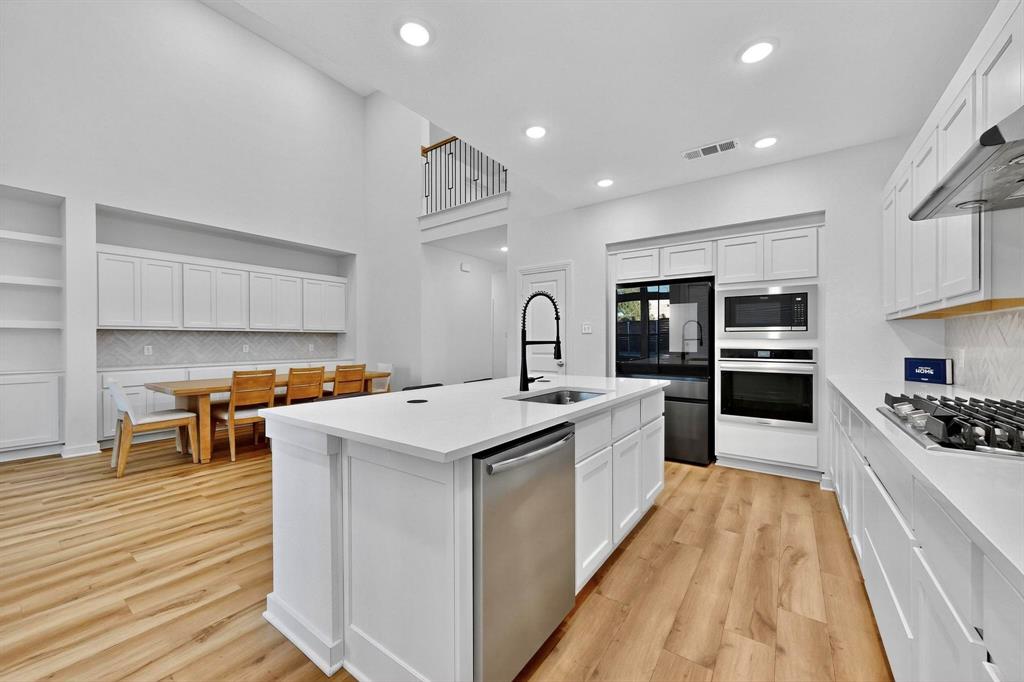 2017 Fall Crk Cove Mesquite, TX 75181 - Photo 3 of 40 Kitchen featuring decorative backsplash, white cabinets, stainless steel appliances, light wood-type flooring, and recessed lighting