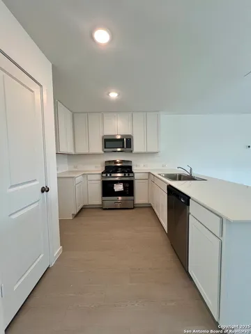 a kitchen with stainless steel appliances granite countertop grey cabinets a stove a sink and a microwave