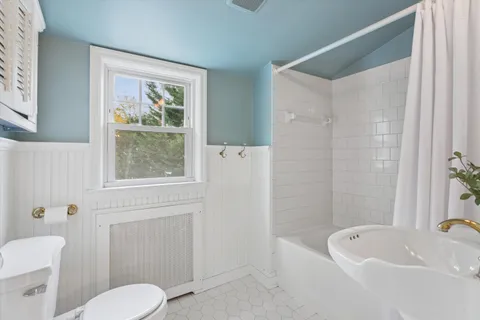 a white bath tub sitting next to a white toilet and a shower
