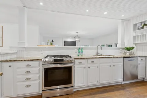 a kitchen with granite countertop white cabinets and appliances