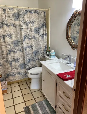 a bathroom with a granite countertop toilet a sink and a mirror