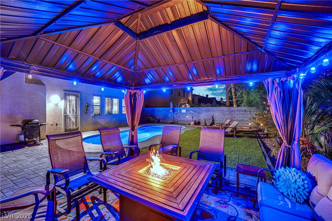 1724 Millstream Way Henderson, NV 89074 - Photo 53 of 60 An inviting backyard haven awaits with a covered patio, tranquil pool, and cozy fire pit.