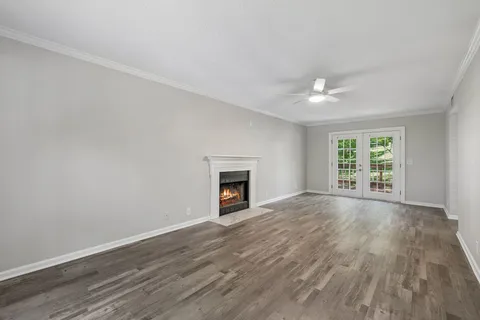 an empty room with wooden floor fireplace and windows