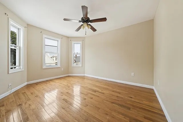 a view of empty room with wooden floor and fan