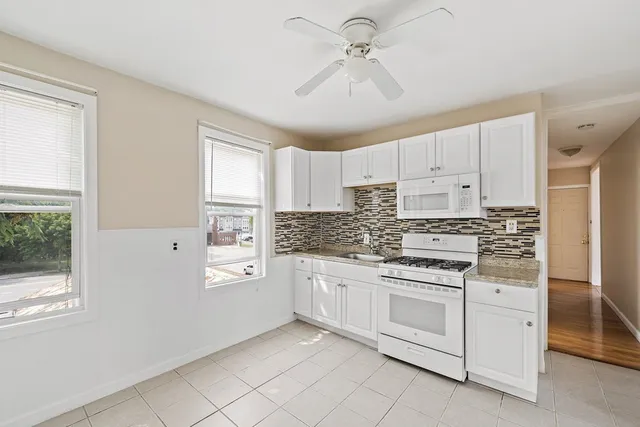 a kitchen with granite countertop white cabinets and white appliances