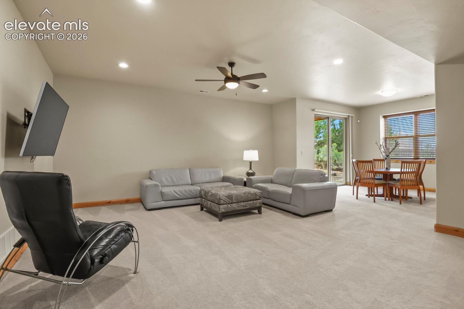 5545 Wilson Road Colorado Springs, CO 80919 - Photo 26 of 48 Recessed lighting, ceiling fan, wall-mounted television bracket, sliding glass door, and large window with wood-finish blinds