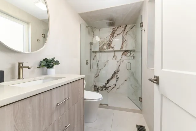 a bathroom with a granite countertop sink a toilet and shower