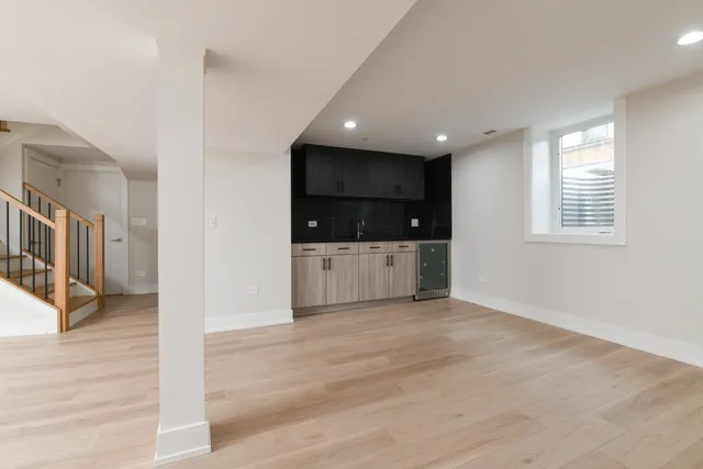 a view of an empty room with a kitchen and microwave