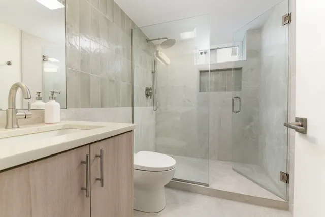 a bathroom with a shower sink vanity and toilet