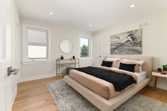 a spacious bedroom with a bed a dresser with wooden floor