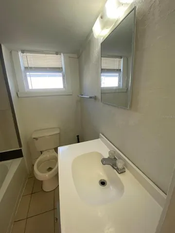 a bathroom with a sink and mirror with toilet