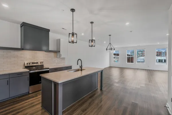 a kitchen with stainless steel appliances granite countertop a sink a refrigerator and a wooden floor